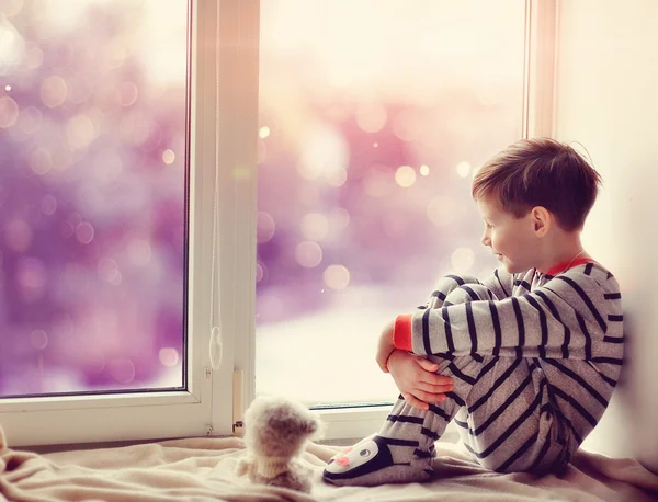 Мальчик в зимнее окно — стоковое фото