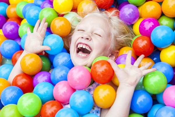 Блондинка девочки весело играя в цветные шарики — стоковое фото